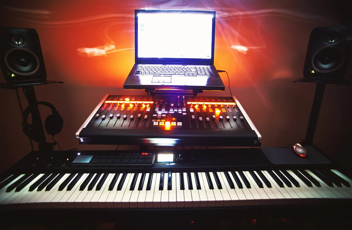 Ein Keyboard, ein Mischpult und ein Laptop zwischen zwei Lautsprechern